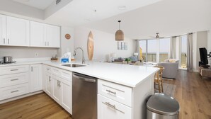 Une cuisine moderne avec des meubles blancs, un lave-vaisselle en acier inoxydable et un grand îlot central.