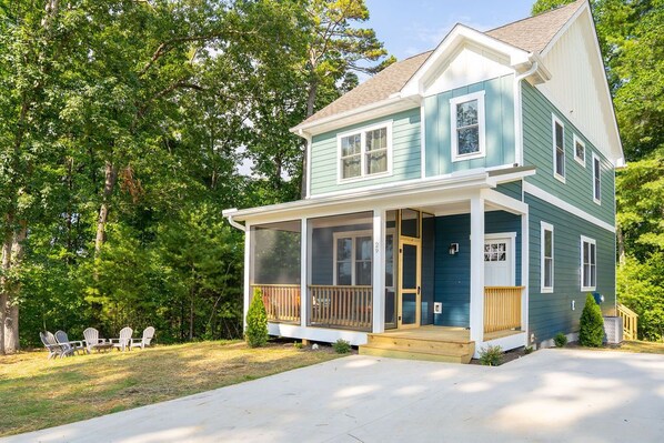 A two-story house with a front porch, a covered entryway, and a small front yard with outdoor seating.
