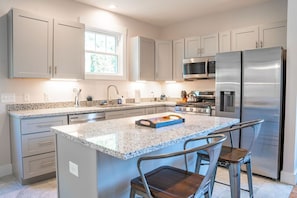 A modern kitchen with granite countertops, stainless steel appliances, and a central island with bar stools.