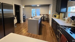 A modern kitchen with a central island, dark cabinetry, and a view to the outside. - Cheerful 3-bedroom minutes from downtown and OCC (Colorado Springs)