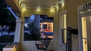 A porch with a swing chair, string lights, and a view of a house. - Cheerful 3-bedroom minutes from downtown and OCC (Colorado Springs)