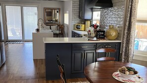 A modern kitchen with a central island, dark cabinetry, and a large window. - Cheerful 3-bedroom minutes from downtown and OCC (Colorado Springs)