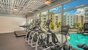 A gym with treadmills, ellipticals, and a pool area with a view of buildings. - All-New, Waterfront Condo Near Downtown Sarasota (Sarasota)
