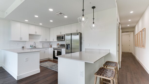A modern kitchen with white cabinetry, stainless steel appliances, and a central island. - All-New, Waterfront Condo Near Downtown Sarasota (Sarasota)