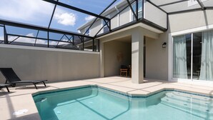 A swimming pool with a glass ceiling, a lounge chair, and a view of the sky.