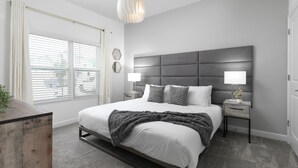 A modern bedroom with a large bed, bedside lamps, a headboard, and a view through the window.