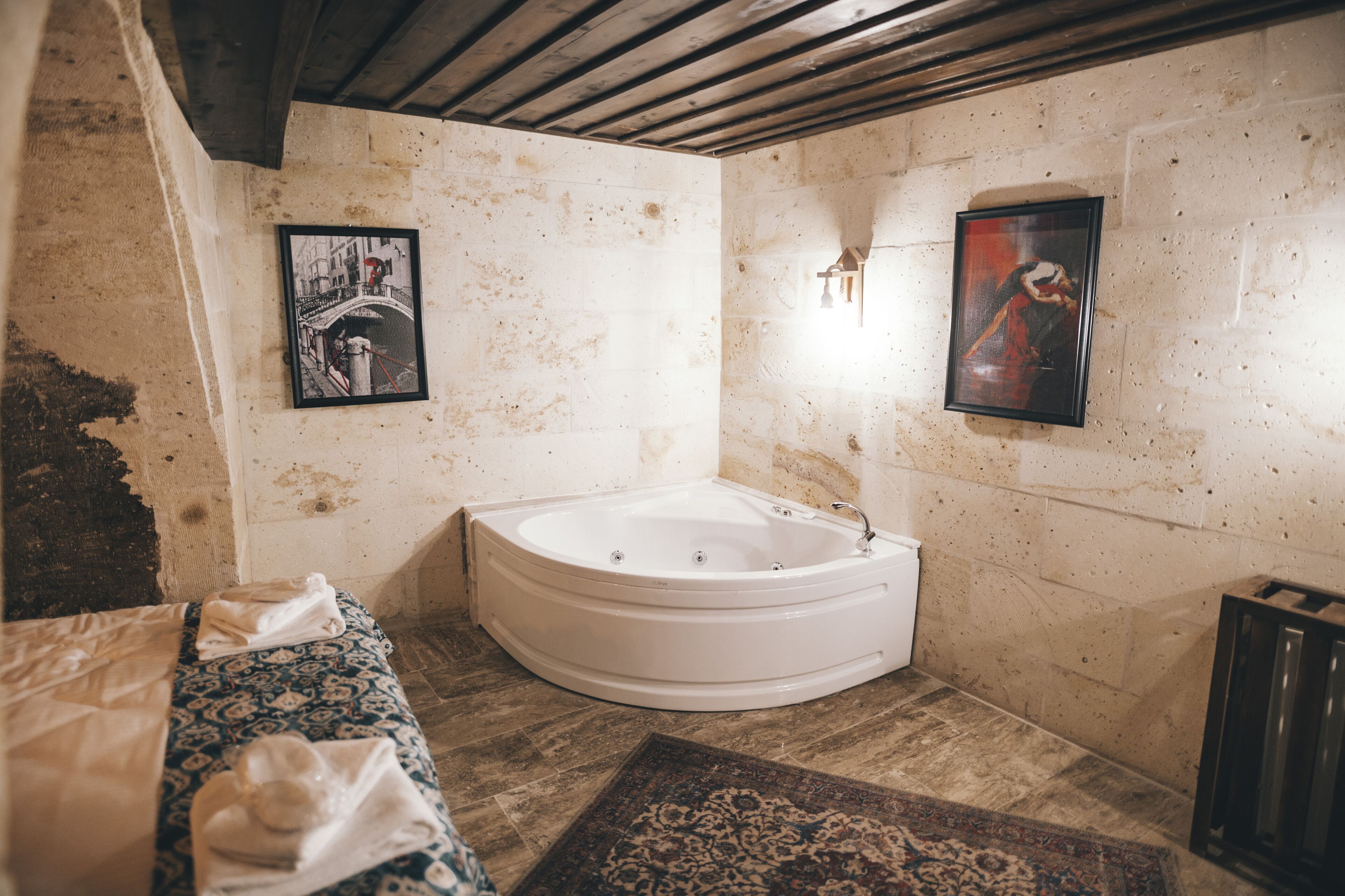 A bathroom with a large bathtub, a patterned rug, and two framed pictures on the walls.