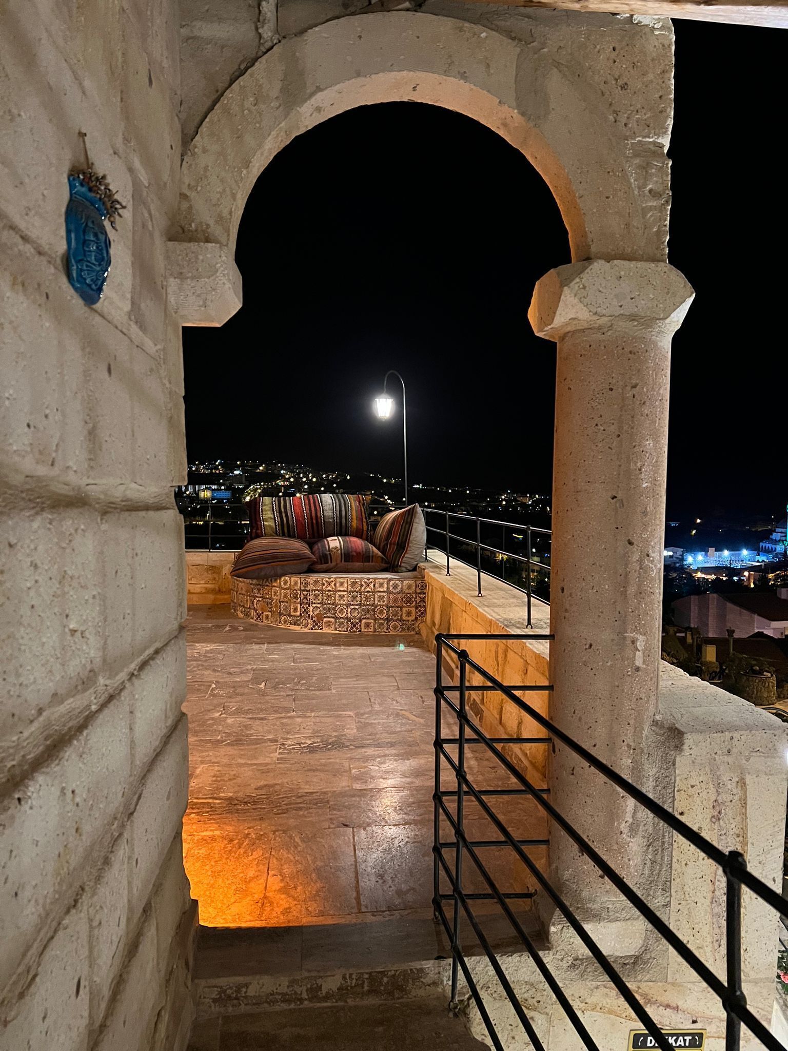 A stone archway leading to a terrace with a view of a cityscape at night.