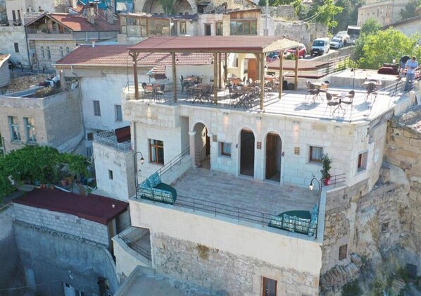 A rooftop terrace with outdoor seating and a stone building with arches. - Tale Cave INN (Ürgüp)
