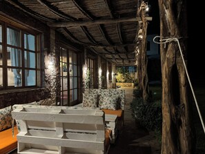 A rustic outdoor seating area with wooden benches and tables, surrounded by stone walls and vegetation. - Family Farm House with Animals near Essaouira and Kaouki Beach (Essaouira)
