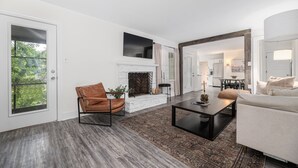 A modern living room with a fireplace, leather chair, and a sofa. - 3,700 sqft-Cozy/Private Villa style Ranch in SouthPark-King en Suite-Winter Rdy! (Charlotte)