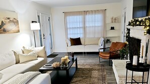 A modern living room with a sofa, coffee table, and a fireplace. - 3,700 sqft-Cozy/Private Villa style Ranch in SouthPark-King en Suite-Winter Rdy! (Charlotte)
