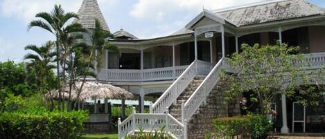 A large, two-story building with a covered porch and a staircase leading to the upper level.