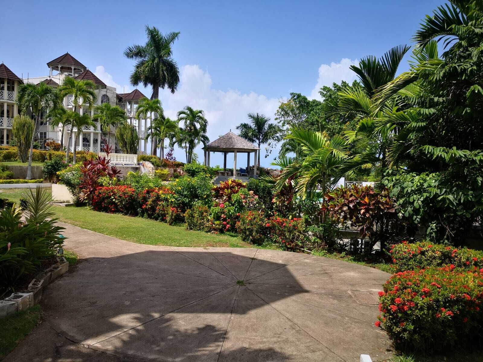 A resort with a central gazebo, palm trees, and a well-maintained garden.