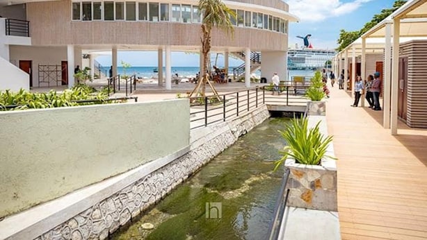 Ett modernt hotell med en central innergård, en pool och utsikt över havet.