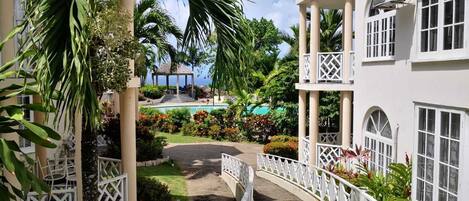 A resort with a pool, palm trees, and a gazebo.
