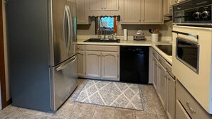 Una cocina con gabinetes de color claro, un refrigerador de acero inoxidable, lavavajillas y horno empotrado.