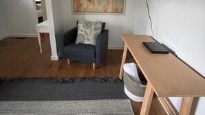 Una sala de estar moderna con un sofá gris, una mesa de madera y un cuadro abstracto grande en la pared.
