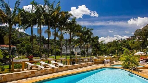 A swimming pool with lounge chairs and palm trees. - Casa do Sol hotel (Petrópolis)