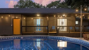 A poolside area with a wooden deck, a pool, and string lights. - Tampa Retreat: 11 Beds, Game Room & Pool! (Tampa)