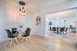 A modern dining area with a round table, black chairs, and a hanging light fixture. - All-Encompassing Retreat w/ Pool & Game Room! (Tampa)