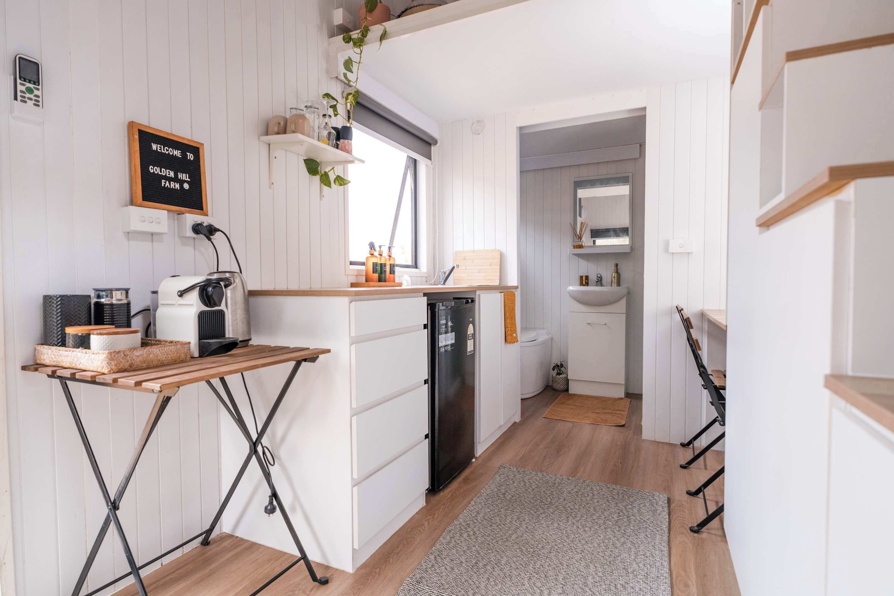 Une cuisine compacte avec des meubles blancs, une table en bois et un four encastré.