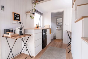 A compact kitchen with white cabinetry, a wooden table, and a built-in oven.