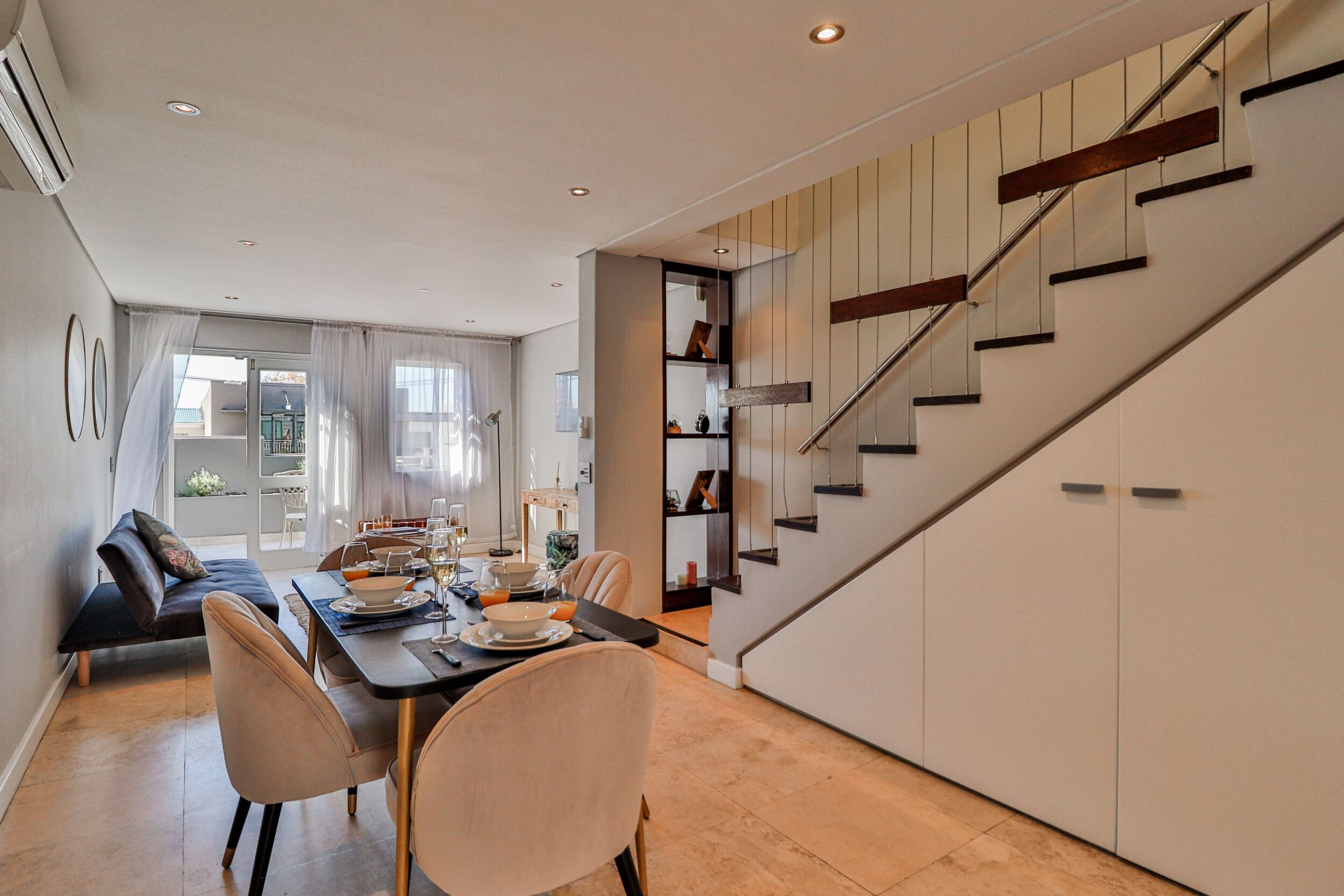 A modern dining area with a staircase leading to a loft bedroom.
