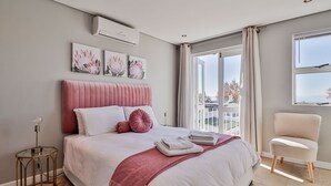 Un dormitorio con una cama grande, vistas al exterior y una silla.