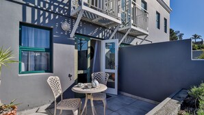 Un edificio moderno con balcón, una puerta y un pequeño patio con dos sillas y una mesa.