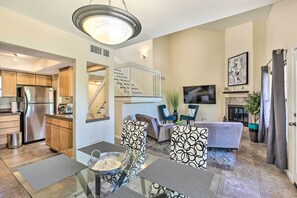A modern kitchen with stainless steel appliances, a dining area with patterned chairs, and a staircase leading to an upper level.