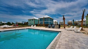 Une piscine dotée d’une terrasse carrelée, de chaises longues et d’un espace clos agrémenté de palmiers.