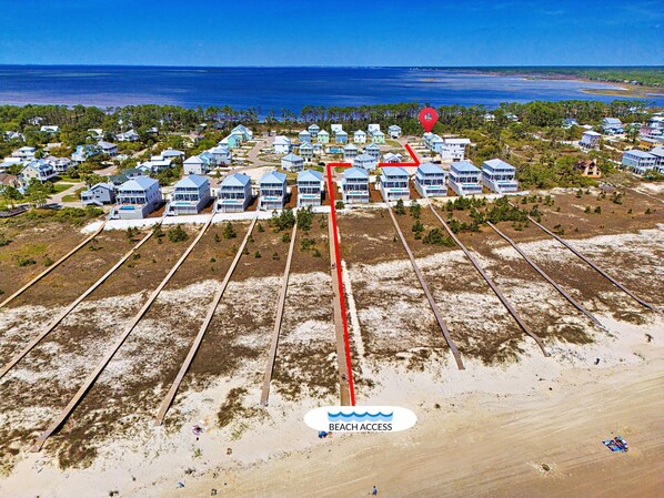 An aerial view of a coastal residential area with houses, a marked beach access path, and a view of the ocean. - Cape San Blas Beach House | Pool & Pickleball | Beach Access (Port St Joe)