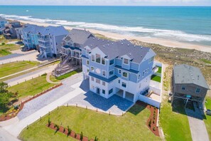 A multi-story residential building with a balcony, located near a beach with ocean views. - Premier Oceanfront Estate w/ Pool, Hot Tubs, Elevator, Theater, and Much More (Hatteras)