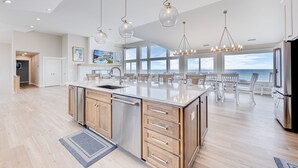 A spacious kitchen with a large island, wooden cabinets, and a view of the ocean.