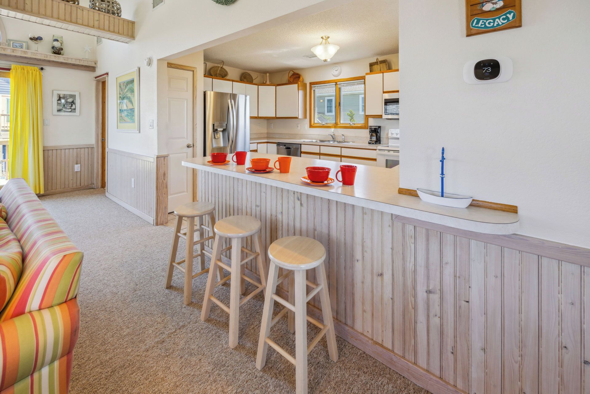 A compact kitchen with a central island, wooden bar stools, and a refrigerator.