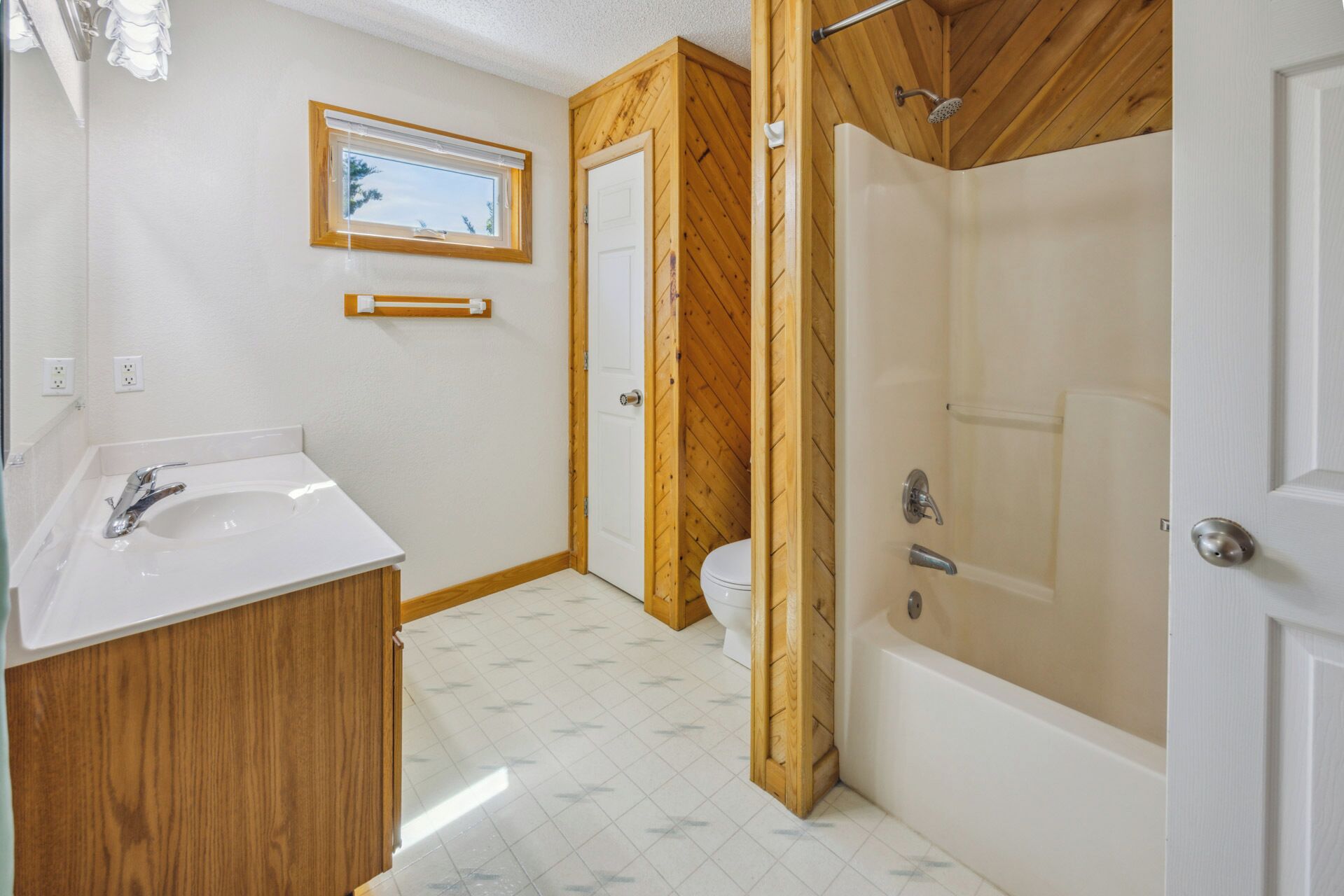 Une salle de bain avec un meuble-lavabo en bois, une baignoire et des toilettes.