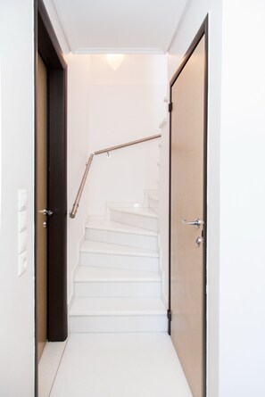 A narrow hallway with white walls and a wooden door on the right. - Luxury Apt in the center of Glyfada (Glyfada)