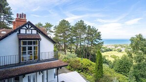 A white house with a balcony overlooking a coastal landscape. - Delightful Holiday Home With sea Views and Hot Tub (Penmaenmawr)
