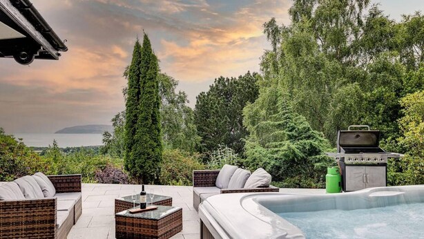 An outdoor patio with wicker furniture, a hot tub, and a grill. - Delightful Holiday Home With sea Views and Hot Tub (Penmaenmawr)