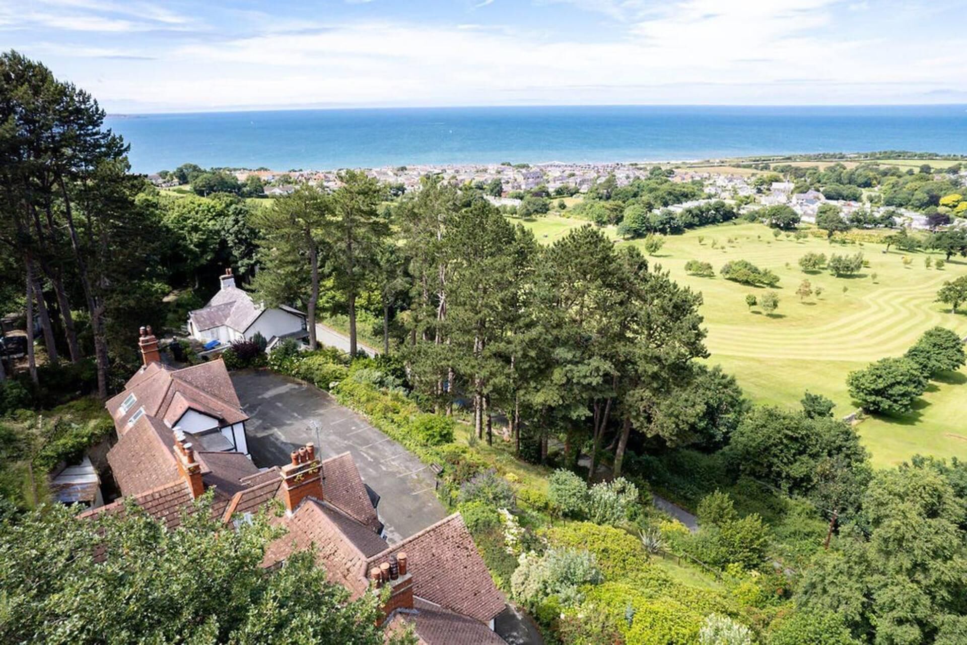 Un quartier résidentiel avec des maisons, un terrain de golf et une vue sur la mer.