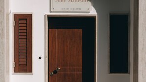 Een hotelentree met een houten deur, een welkomstmat en een bord boven de deur met de tekst 'Suite Matteotti DIMORA DI CHARME'.