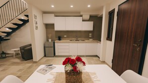 Een moderne keuken met witte kasten, een houten deur en een eethoek met een tafel en stoelen.