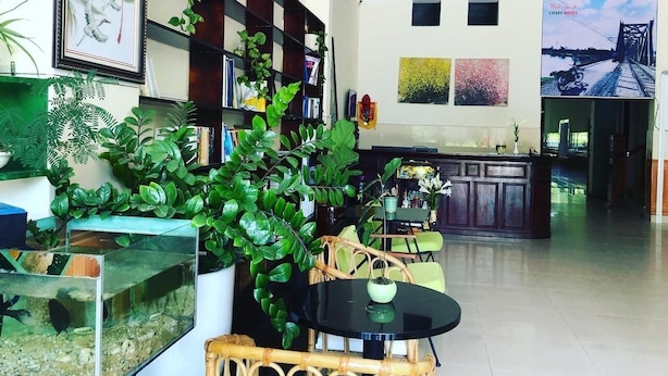 A spacious lobby with a reception desk, seating area, and a large window with a view of a bridge. - Chapi Hotel (Dong Hoi)