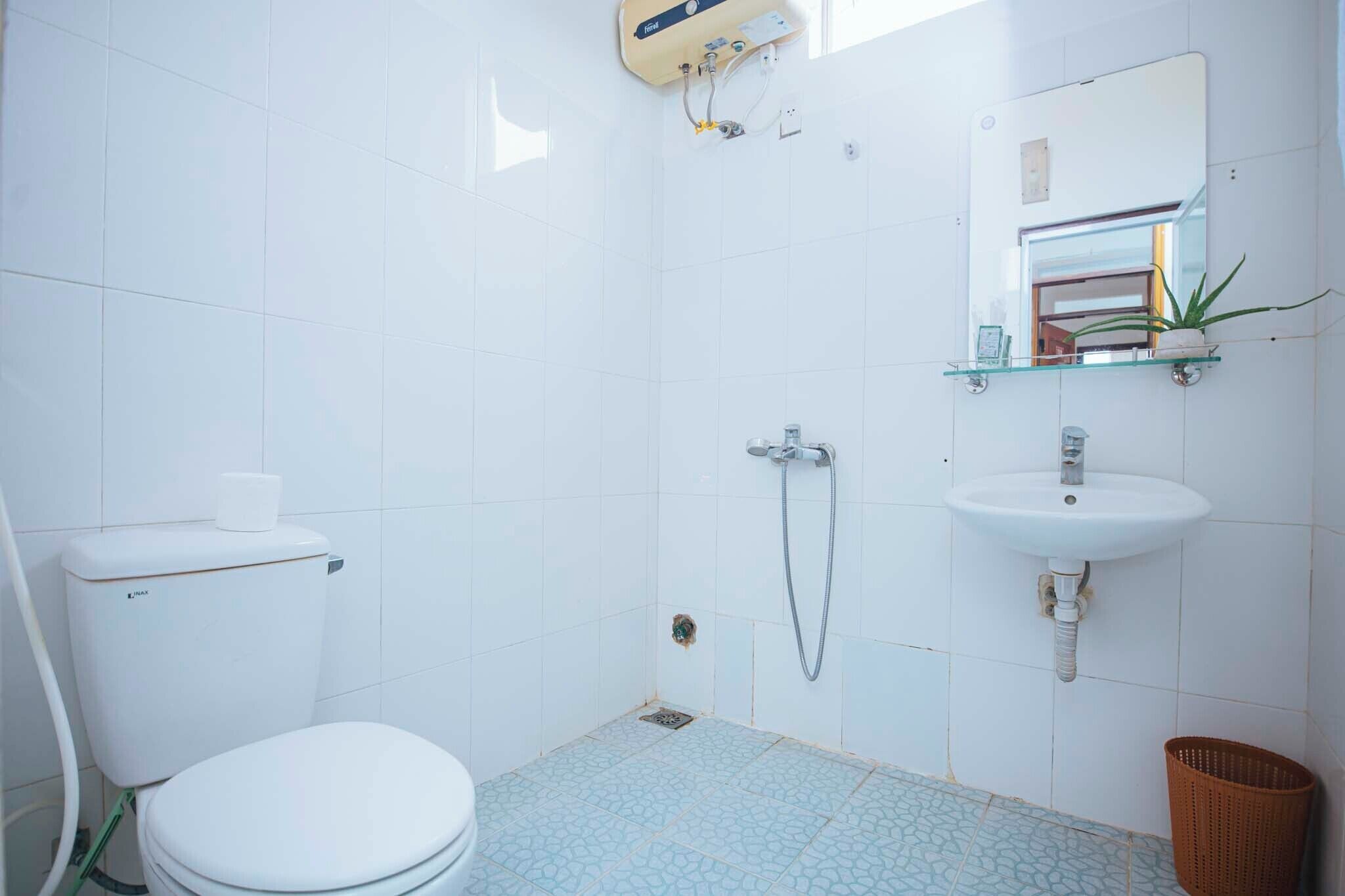 A bathroom with a toilet, shower, sink, and a mirror.