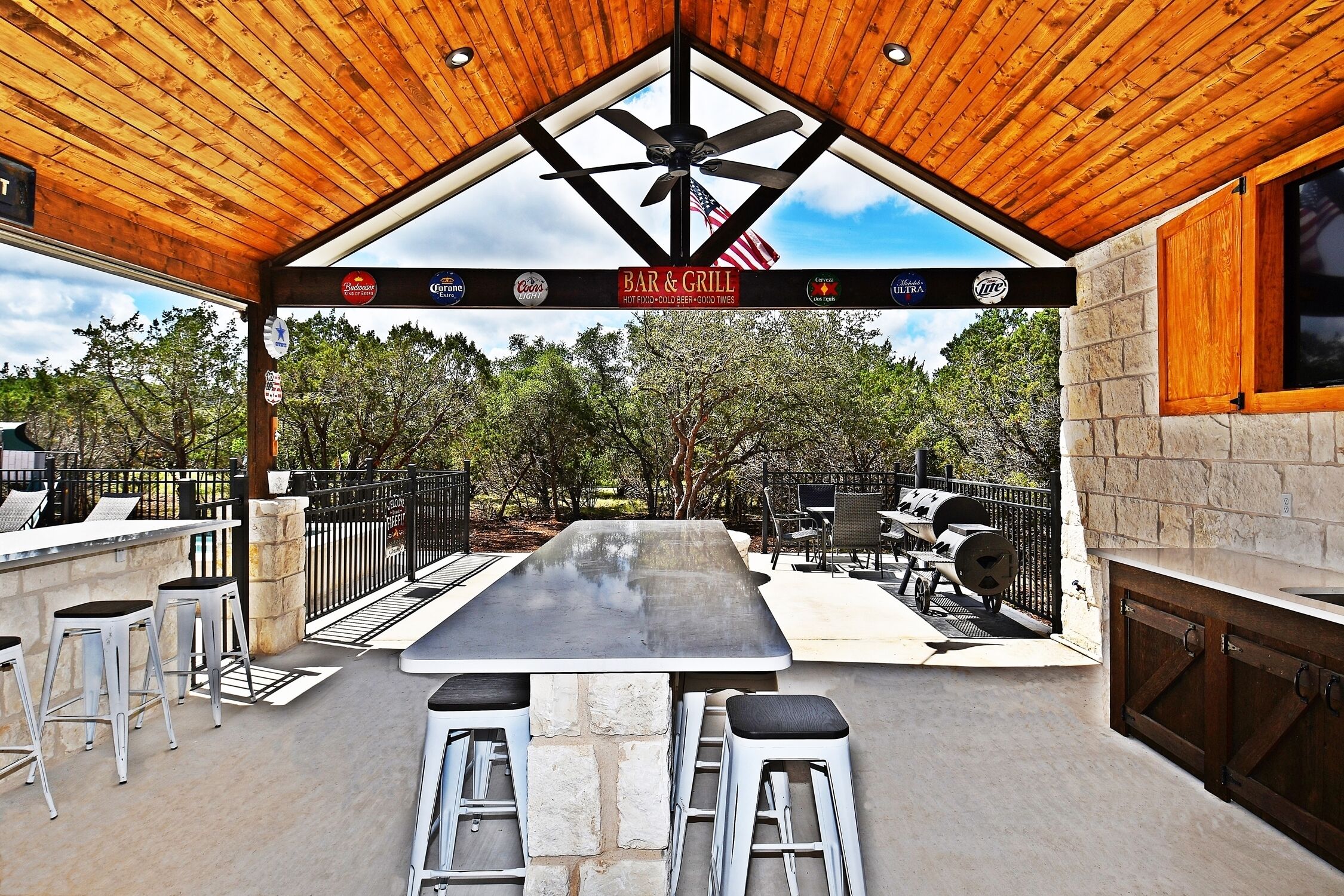 An outdoor patio with a bar and grill area, stone seating, and a grill.