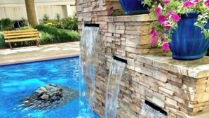 Ein Pool mit einem Wasserfall aus Stein und einer Sitzbank.