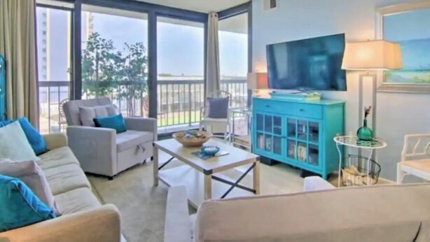 Ein geräumiges Wohnzimmer mit einer Couch, einem Couchtisch, einem Fernseher und einem Schrank.