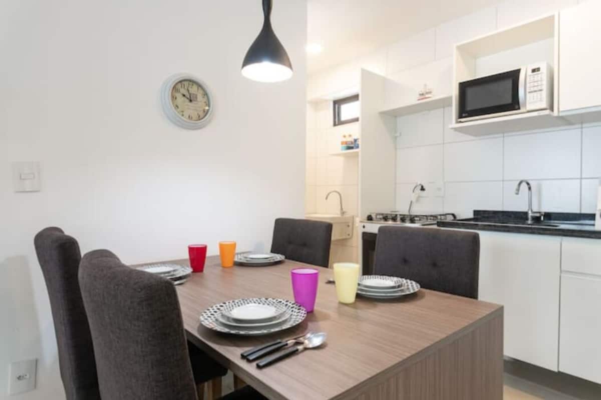 A modern kitchen with white cabinets, a microwave, and a dining area with a wooden table and chairs.