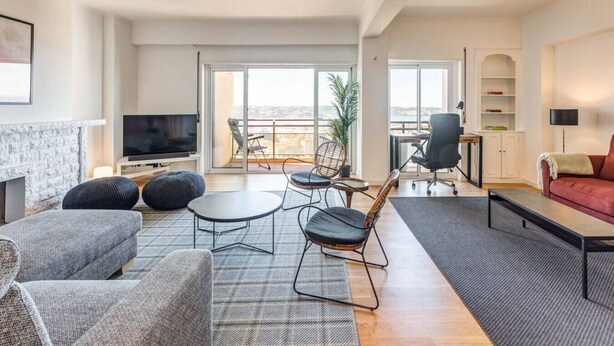 A modern living room with a fireplace, comfortable seating, a flat-screen TV, and a balcony with a view. - Ajuda · Belvedere TM Flat With a Magnificent View (Lisboa)